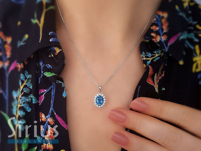 Oval pendant with blue topaz and 14 diamonds – 14K white gold
